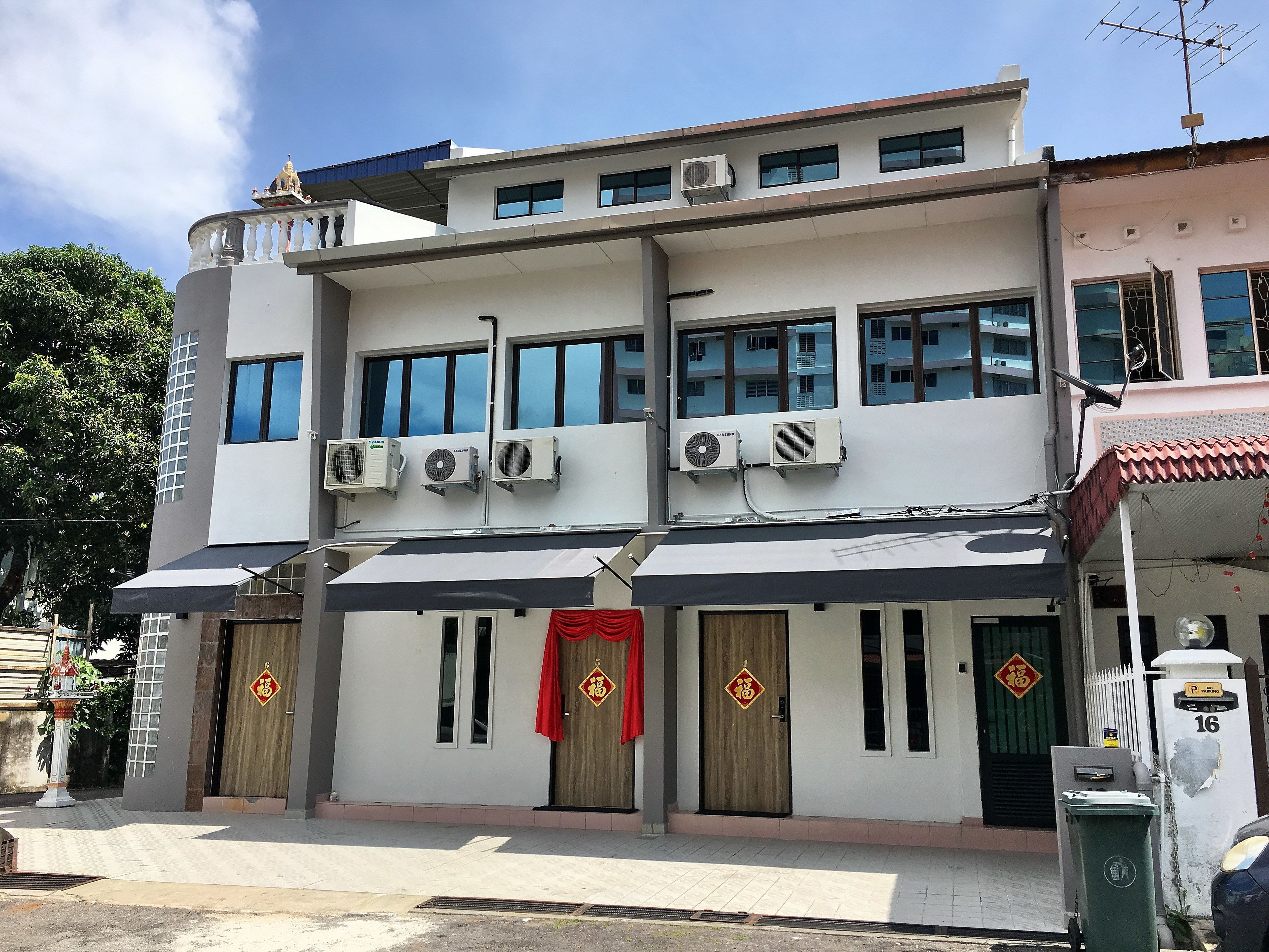 A two-story building with multiple air conditioning units, a gated entrance, and a small statue on the roof.