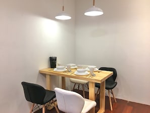 A dining area with a wooden table set for four, two chairs, and a black vase on the table. - iBook7 - 2 Bedroom Gurney Studio Suite by iBook Homestay (George Town)