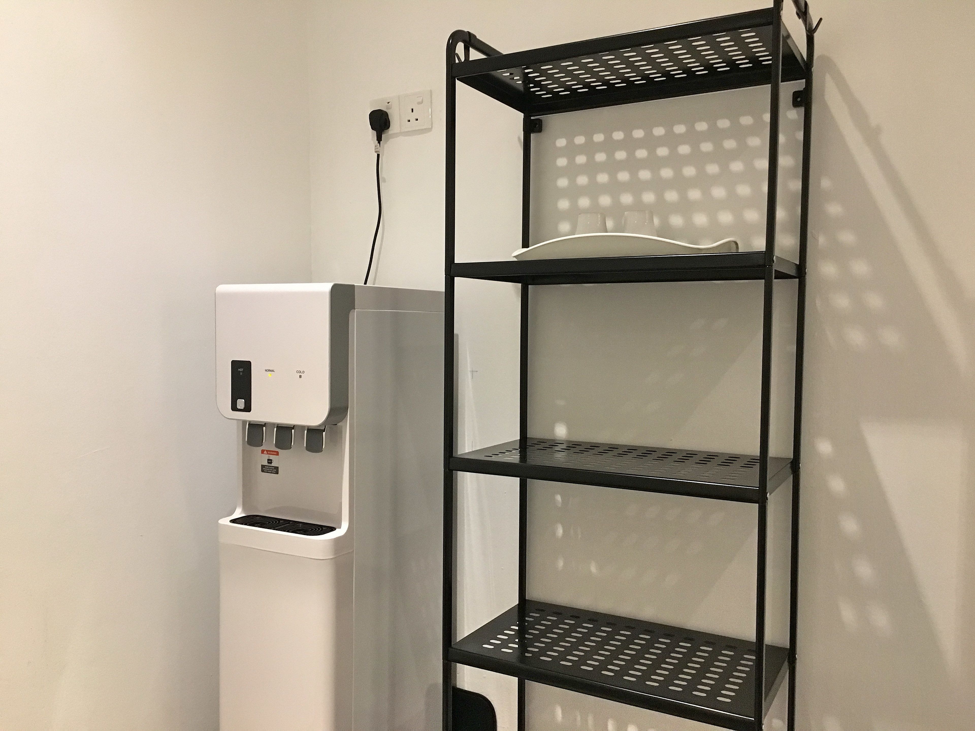 En vattenautomat med en hylla av metall placerad bredvid.