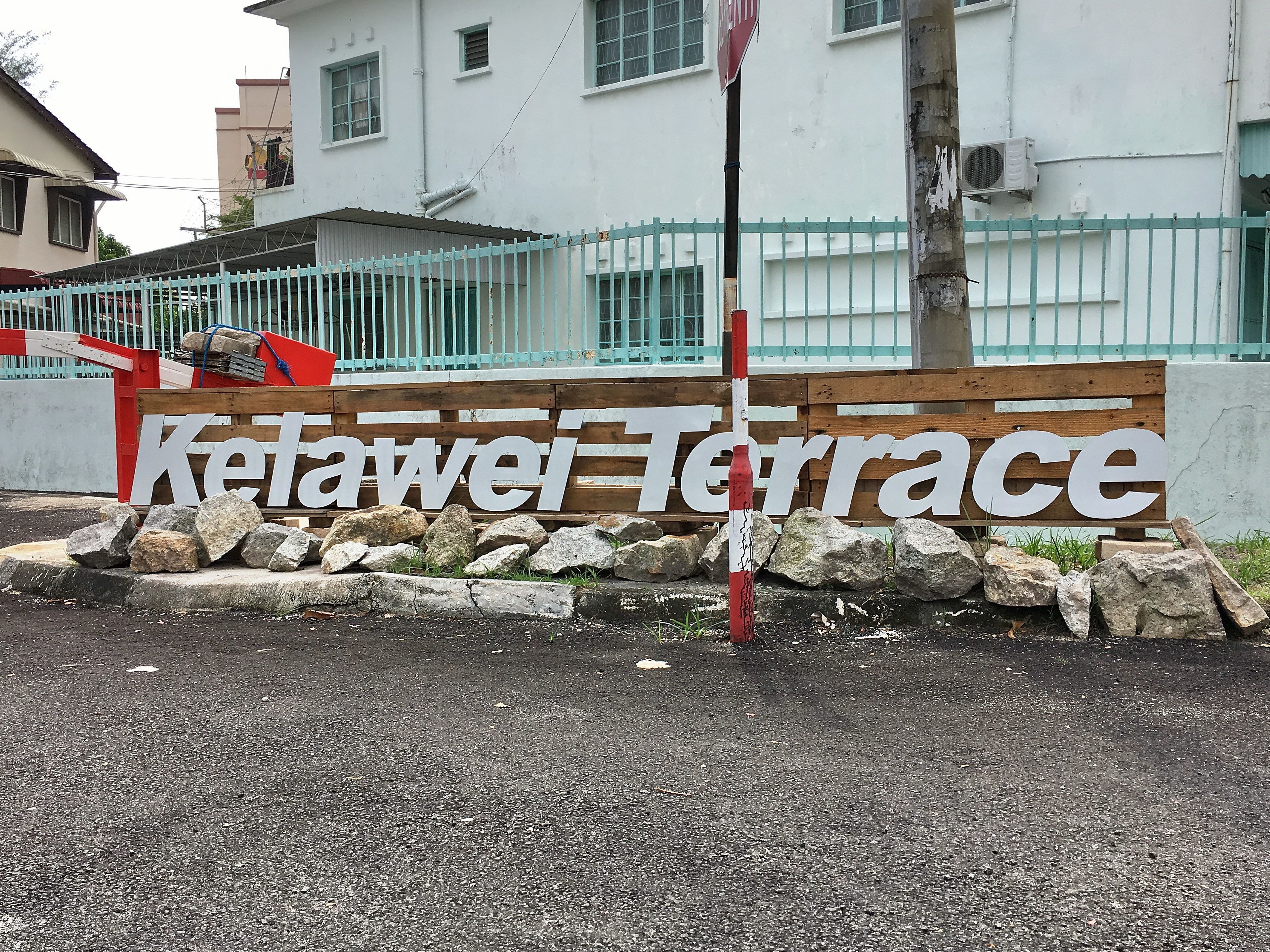 A sign for "Ketawei Terrace" with a wooden fence and rocks in front.