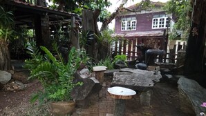 Un jardín rústico con un banco de madera, un sendero de piedra y plantas en macetas.