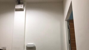 A narrow hallway with a white door, a small white object on the wall, and a wooden panel on the right. - Sleepwell@Naiyang (Sa Khu)