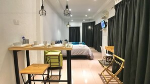 A hotel room with a bed, a desk with a chair, a small table with a chair, and a TV on the wall. - iBook9 Deluxe Family Suite by iBook Homestay (George Town)