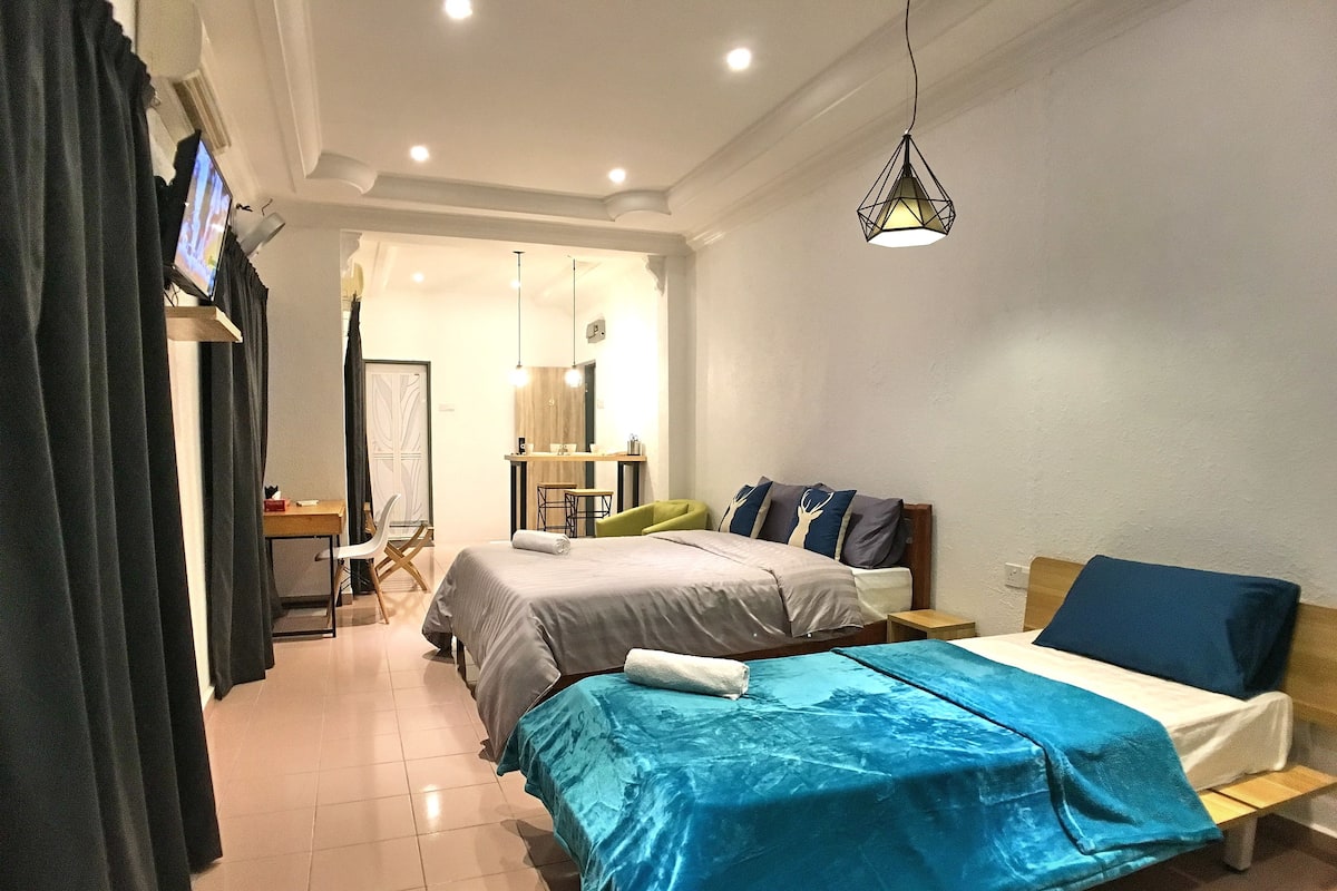 A modern bedroom with a large bed, a smaller bed, a desk, and a chair.