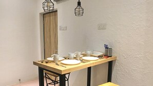 A small dining area with a wooden table and chairs, a white wall, and a door in the background. - iBook9 Deluxe Family Suite by iBook Homestay (George Town)
