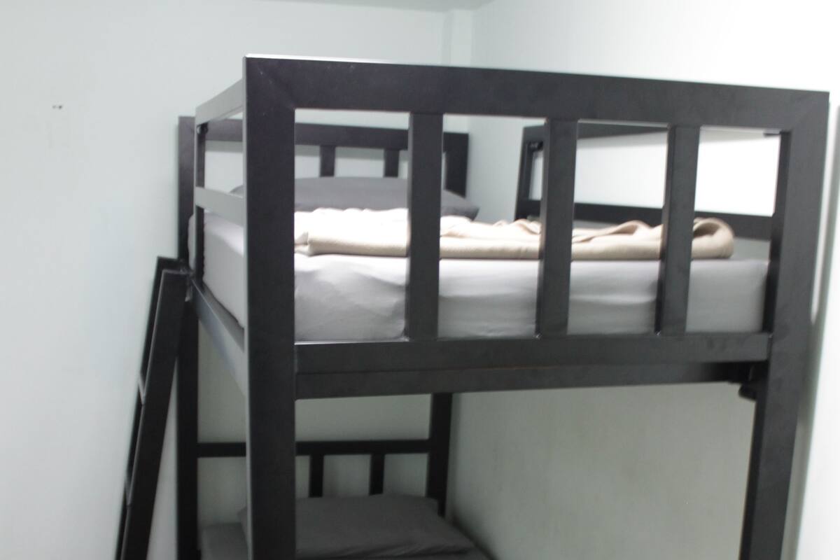 Ein Etagenbett mit einer Leiter, einer Matratze und einem Kopfkissen im oberen Bett.