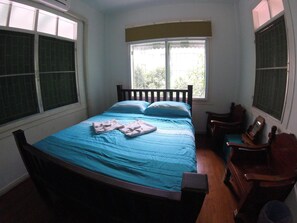 A bedroom with a bed, a wooden chair, and a window with blinds. - The Oasis Hostel - Adults Only (Bangkok)