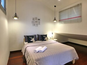 A neatly made bed with a striped blanket, two bedside lamps, and a wall with framed pictures. - iBook10 Deluxe Loft Suite Room by iBook Homestay (George Town)
