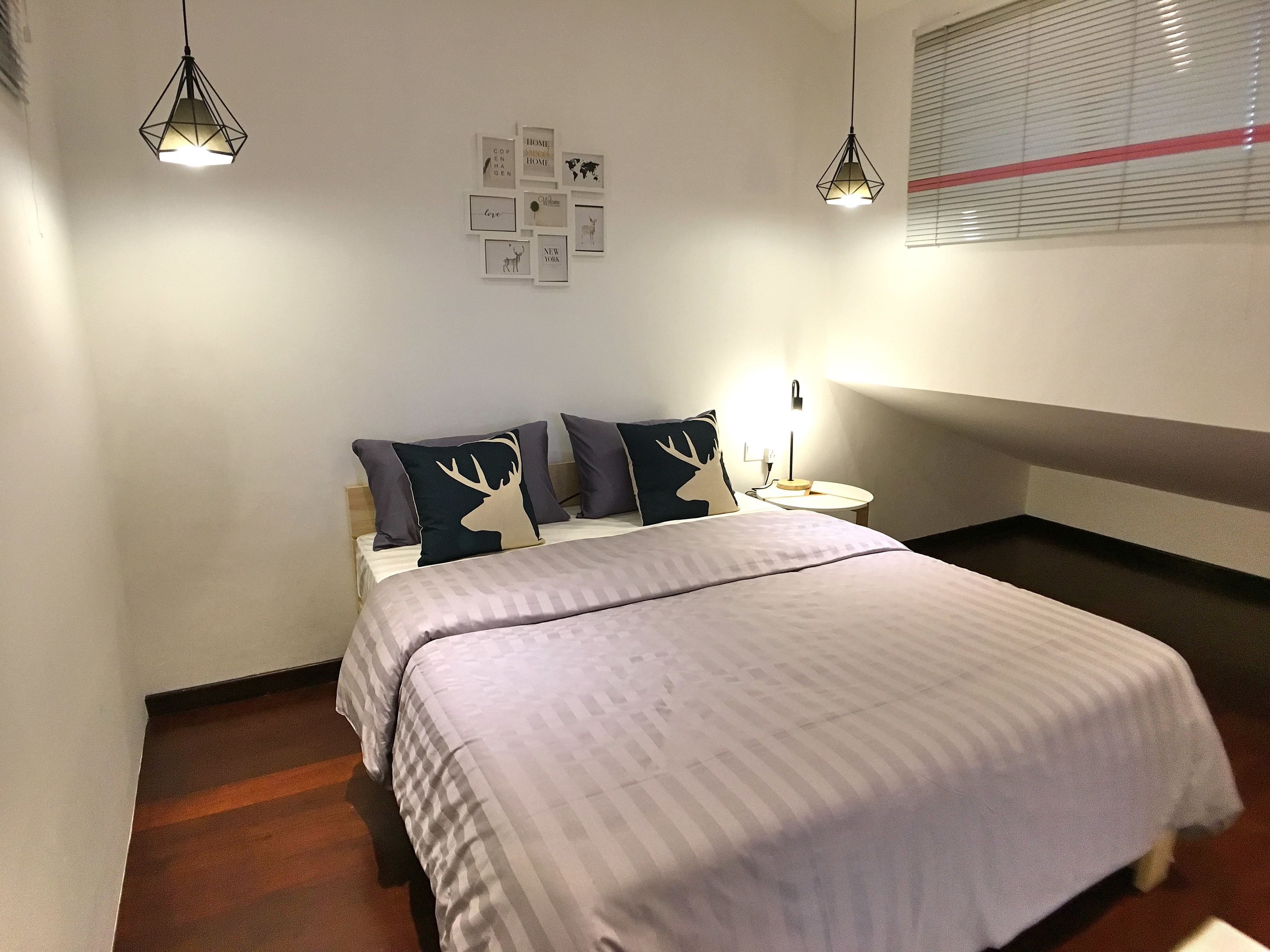 A neatly arranged bedroom with a bed, two bedside lamps, a nightstand, and a wall-mounted light fixture.