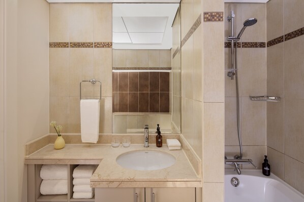 Une salle de bain équipée d’un lavabo, d’un miroir, d’un porte-serviettes et d’une douche.