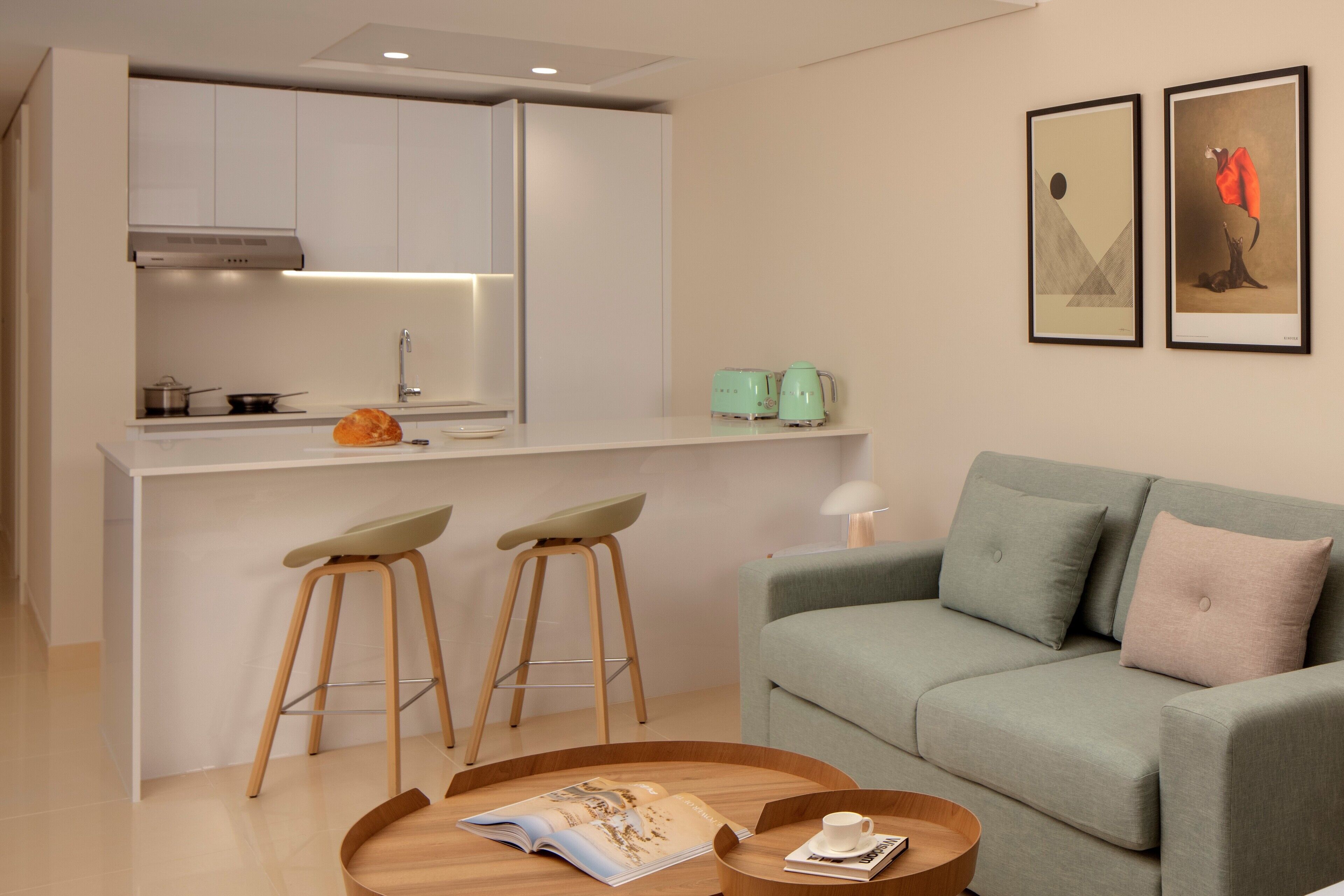 A modern living space with a kitchen, two bar stools, a sofa, and a coffee table.