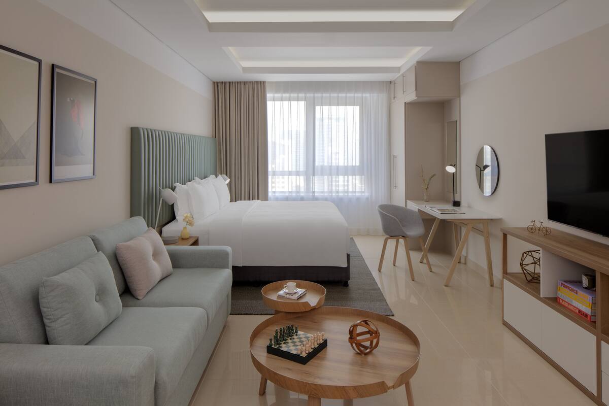 Een moderne hotelkamer met een bed, een bank, een bureau, een televisie en een salontafel.