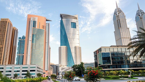 A cityscape with modern skyscrapers, including a distinctive curved building and a tall, pointed structure.