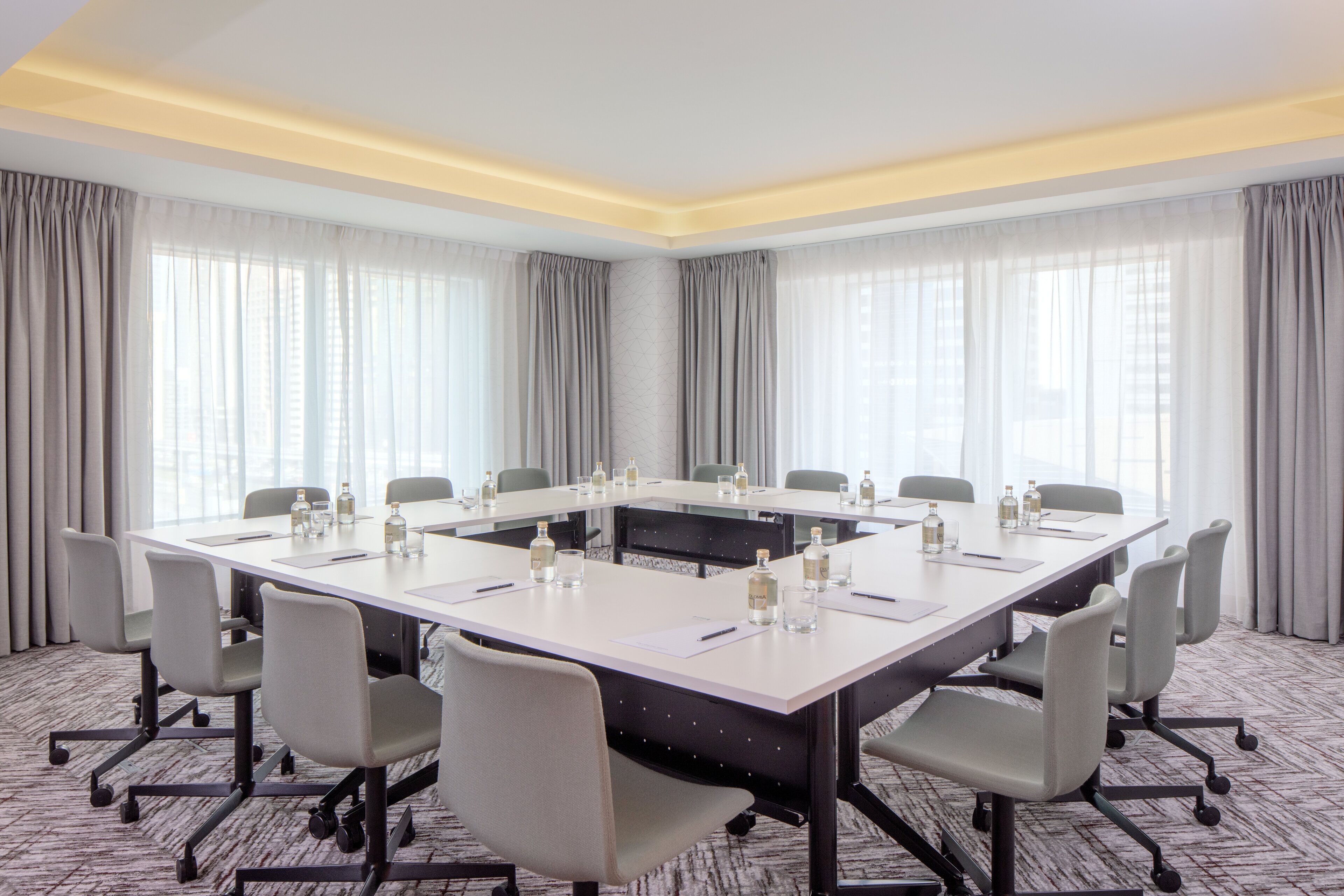 A conference room with a large table, chairs, and a carpeted floor.