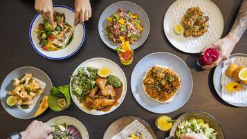Une table à manger avec différents plats et des personnes qui mangent.