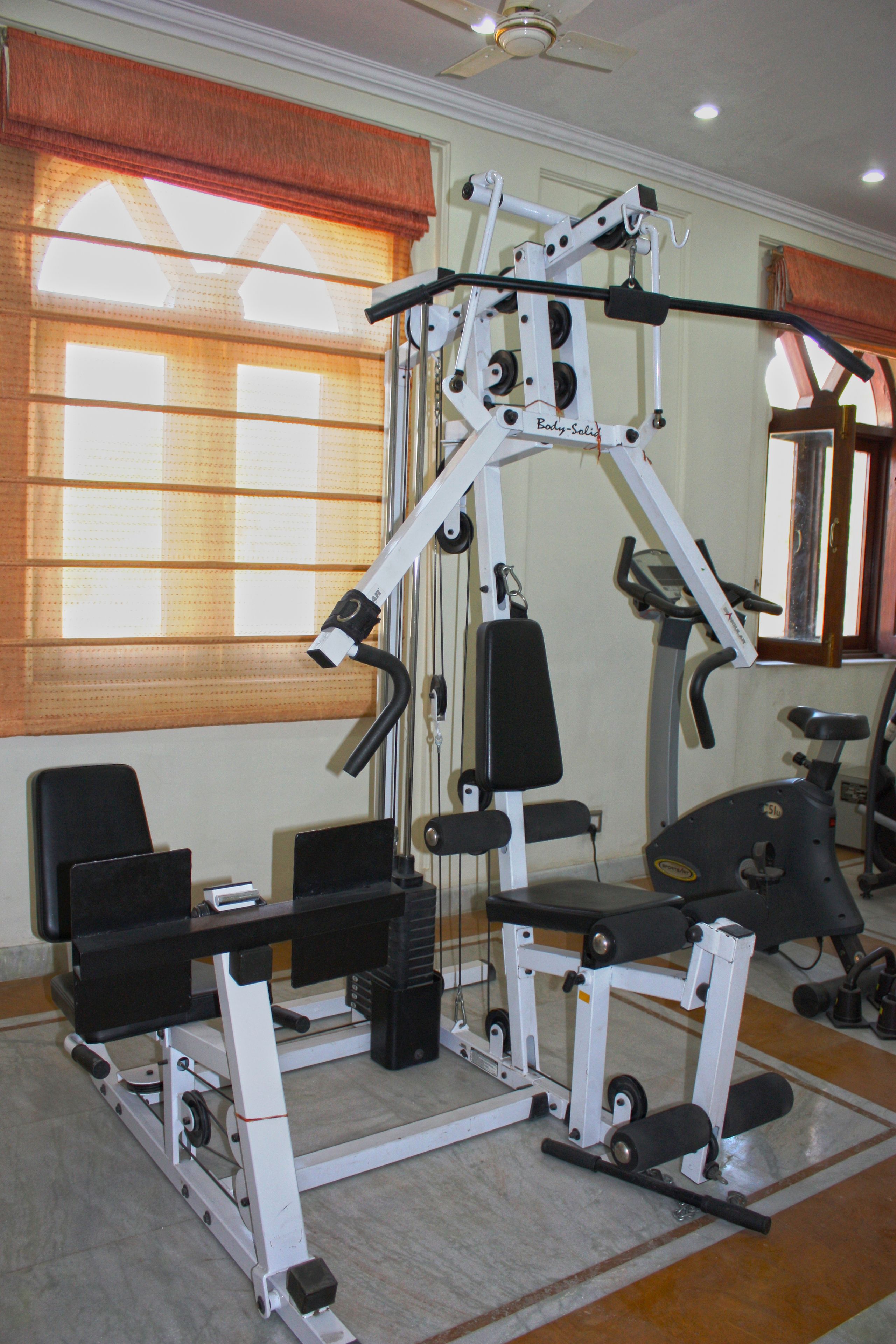 Un gimnasio con varios equipos de ejercicio, incluyendo una prensa de banca, una estructura para sentadillas y una cinta de correr.