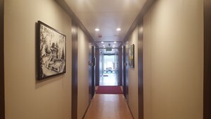 Ein Flur mit Kunstwerken an den Wänden, einem roten Teppich und einem Hinweisschild für den Ausgang.