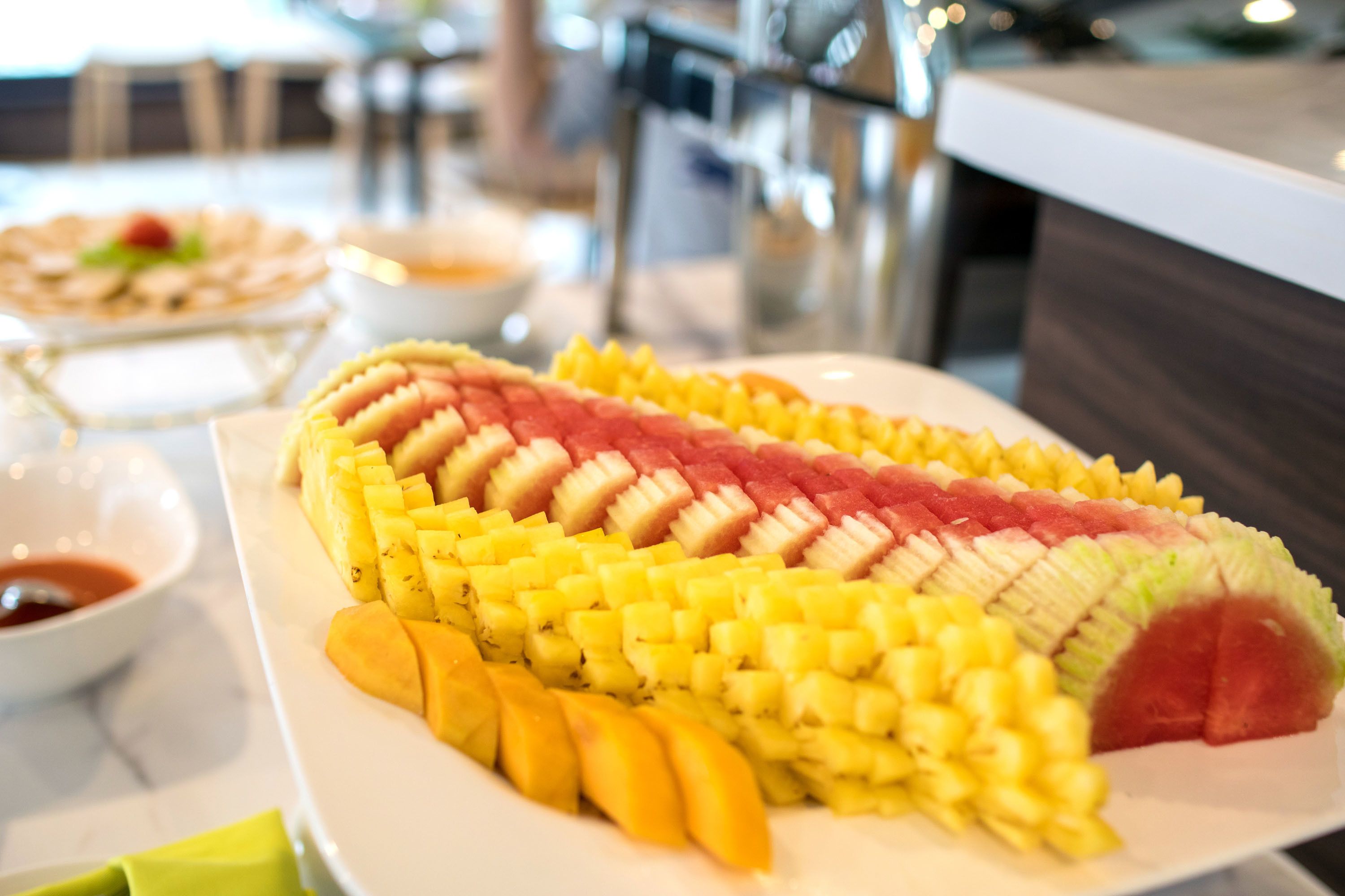 Una fuente de fruta dispuesta en un diseño, con un cuenco de salsa al lado.