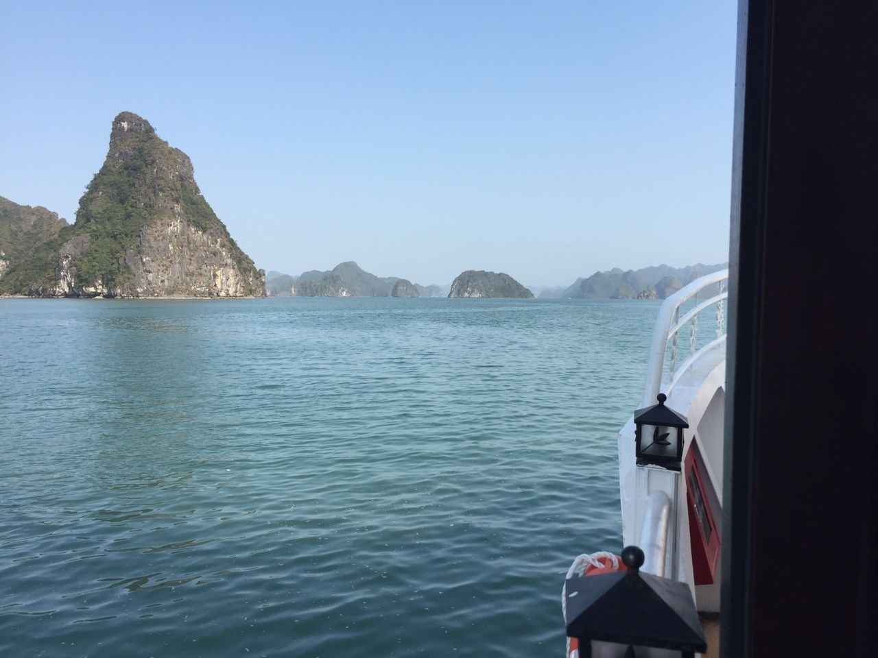 A boat with a view of a mountainous island and calm water.