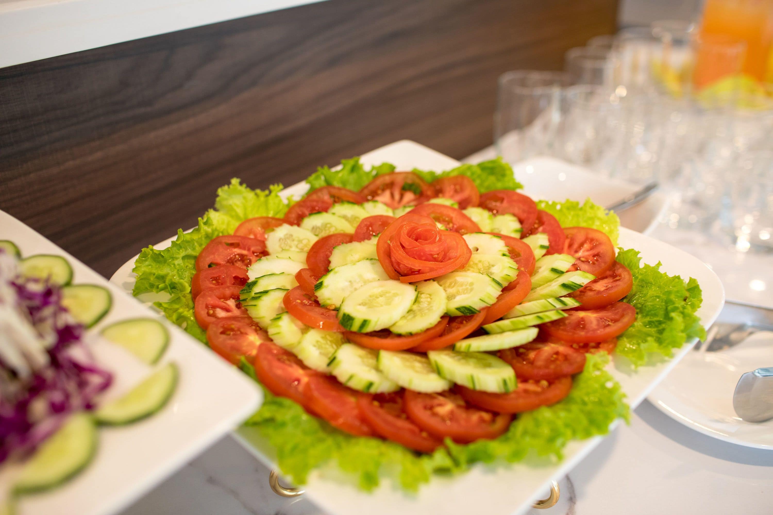 A salad with a rose design made of vegetables on a white plate.