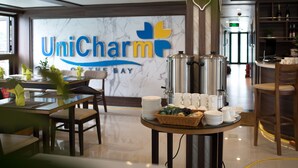Eine Hotellobby mit Rezeption, einem Selbstbedienungsbereich mit Tellern, Tassen und einer Kaffeestation.