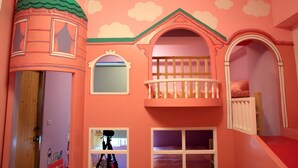 Una sala de juegos infantil con temática de castillo, que incluye una torre, balcón y ventanas.