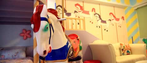 A carousel horse in a room with a bed, a sofa, and a wall with horse decals.