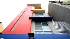 Un edificio moderno con fachada roja y azul, una ventana pequeña y una cámara de seguridad.