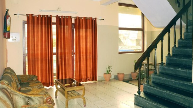 A living room with a sofa, a coffee table, and a staircase. - Hotel Golden (Haridwar)
