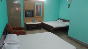 A room with two beds, a television, a wardrobe, and a small table with items on it. - Hotel Golden (Haridwar)