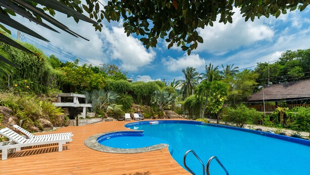 A swimming pool with wooden deck and lounge chairs, surrounded by greenery and a clear sky. - Dendi Resort Phu Quoc (Phu Quoc)
