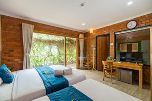A hotel room with two beds, a desk, a television, and a small refrigerator.