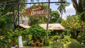 A wooden sign reading "Welcome to Dendi Bungalow" amidst lush greenery and a patio area with wooden furniture. - Dendi Resort Phu Quoc (Phu Quoc)