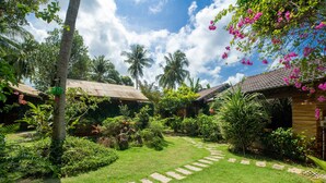 A lush garden with a stone pathway leading to a wooden building with a tiled roof. - Dendi Resort Phu Quoc (Phu Quoc)