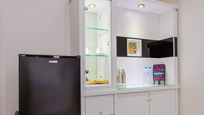 Una cocina con un refrigerador negro, un gabinete de vidrio con estante y una pizarra con texto.