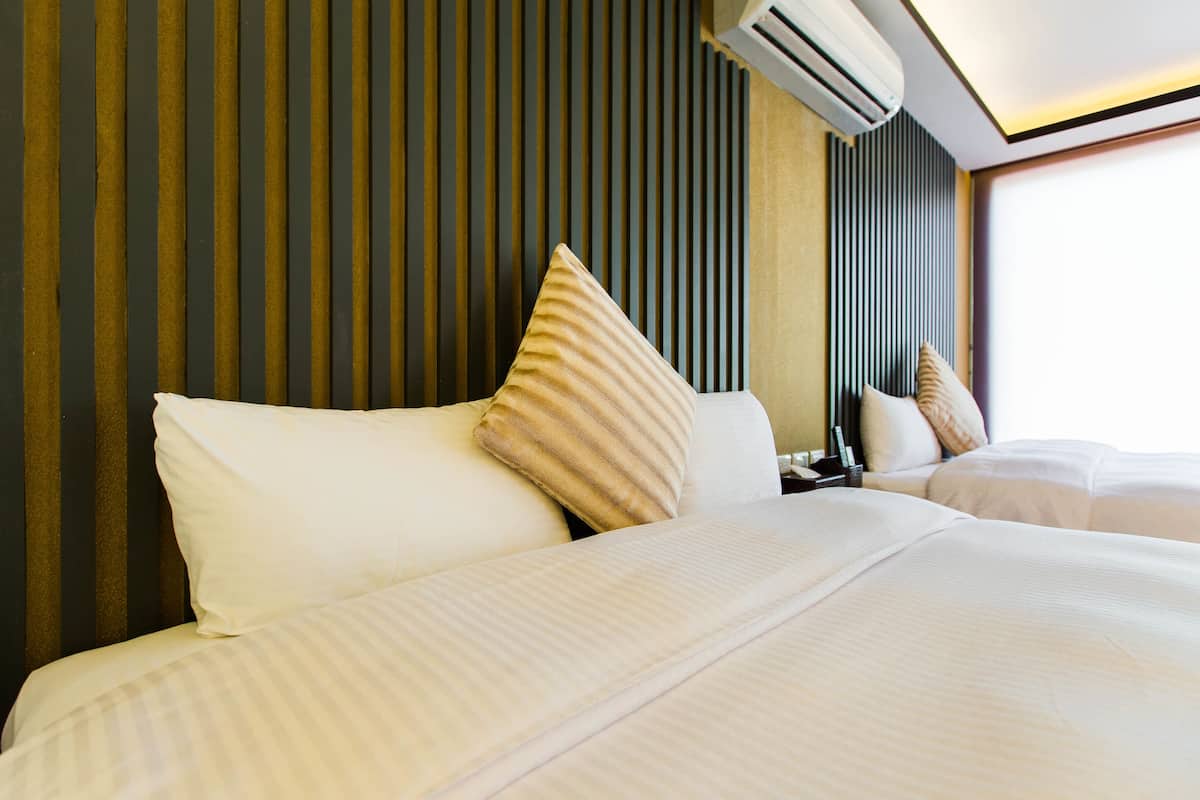 A hotel room with a large bed, a mirror, and a wall with vertical lines.