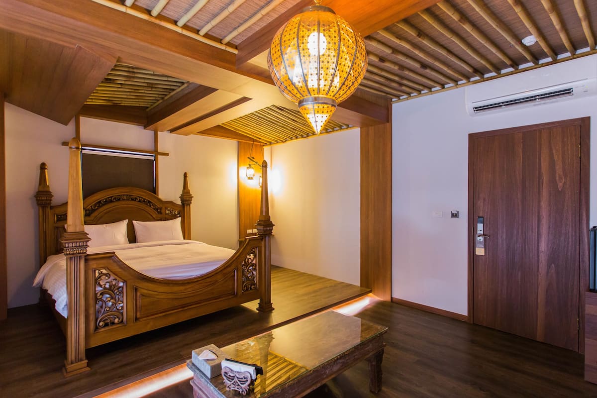 A wooden four-poster bed with a nightstand, a hanging lantern, and a wooden door.