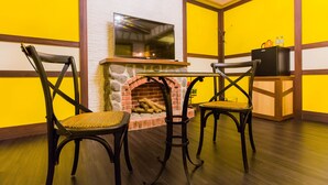 Habitación con chimenea de piedra, dos sillones, un televisor y una mesita.