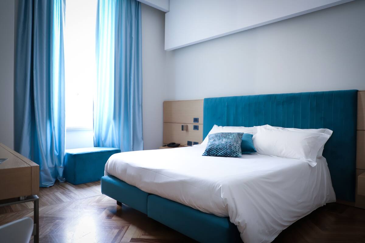 Une chambre à coucher avec un lit, un bureau et une fenêtre avec des rideaux.