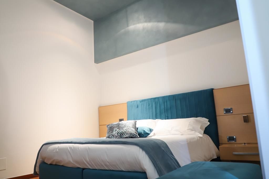 A modern hotel room with a large bed, a nightstand, and a built-in wardrobe.