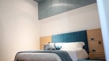 A modern hotel room with a large bed, a nightstand, and a built-in wardrobe.