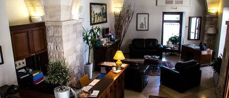 A spacious lobby with a reception desk, seating area, and a stone column.