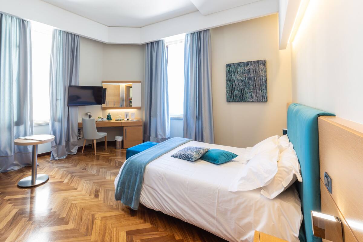 Une chambre d’hôtel avec un lit, un bureau, une chaise, une télévision et un tableau au mur.