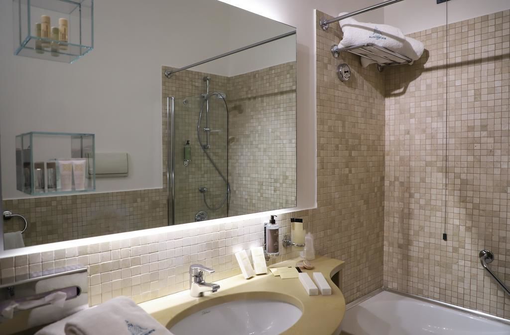 Ein modernes Badezimmer mit einem großen Spiegel, einem Waschbecken, einer Dusche und einem Handtuchhalter.
