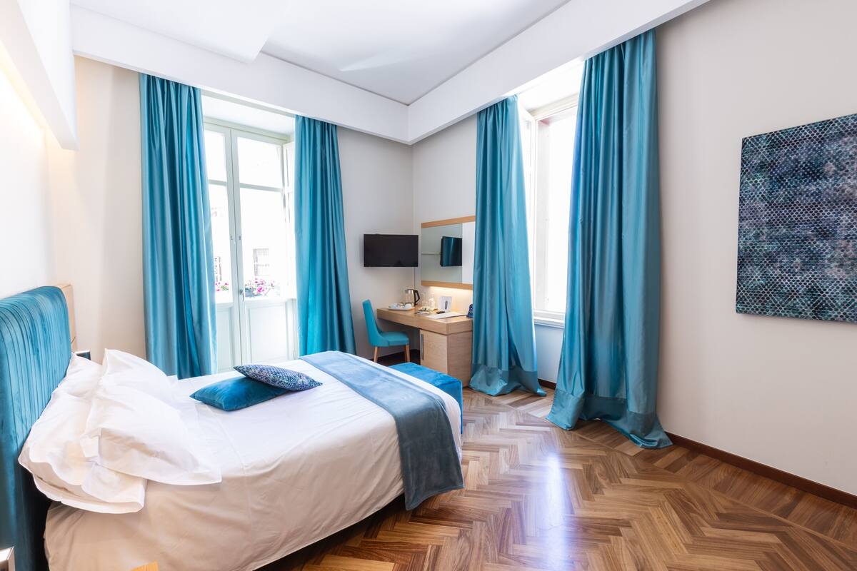 Une chambre d’hôtel avec un lit, un bureau, une chaise et un téléviseur.