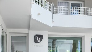 Interior moderno de hotel con una escalera que lleva a un balcón, una recepción y una zona de estar con sillones.