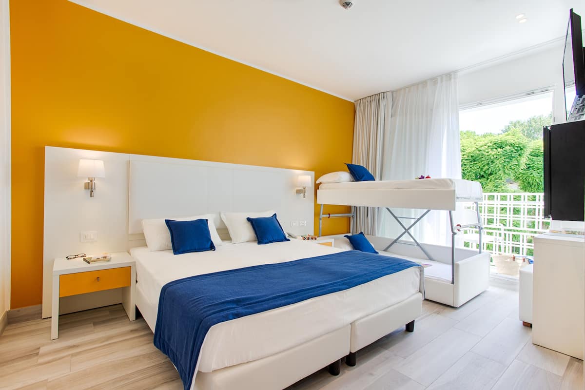 Una habitación de hotel moderna con una cama grande, una cama litera y un balcón con vistas.