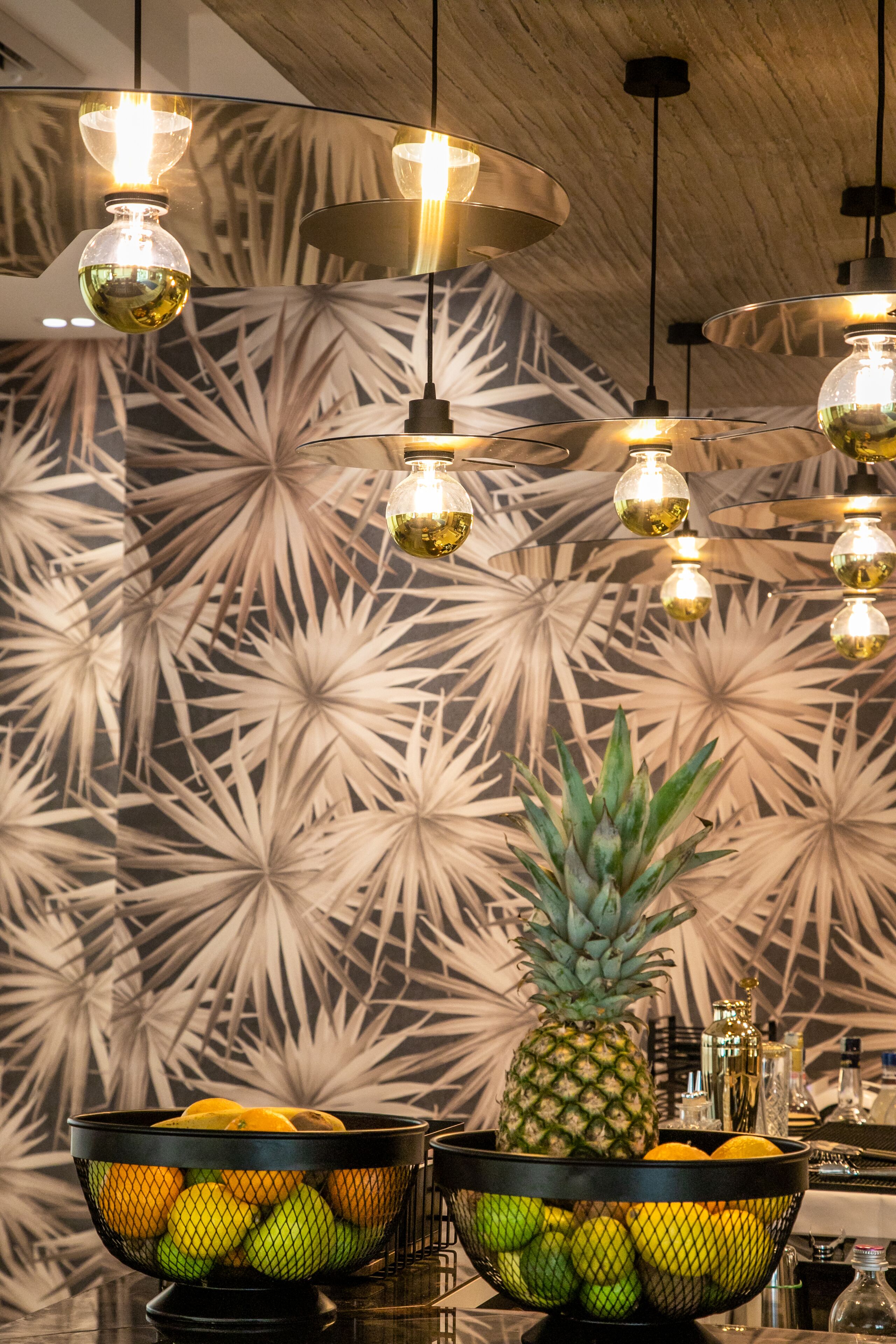 Una habitación con pared estampada, una piña y dos cestas de fruta.