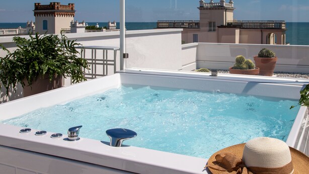 Una piscina en la azotea con vistas al mar y edificios.