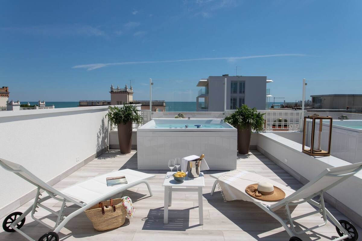 Una terraza en la azotea con sillones de descanso, un jacuzzi y vistas al mar.